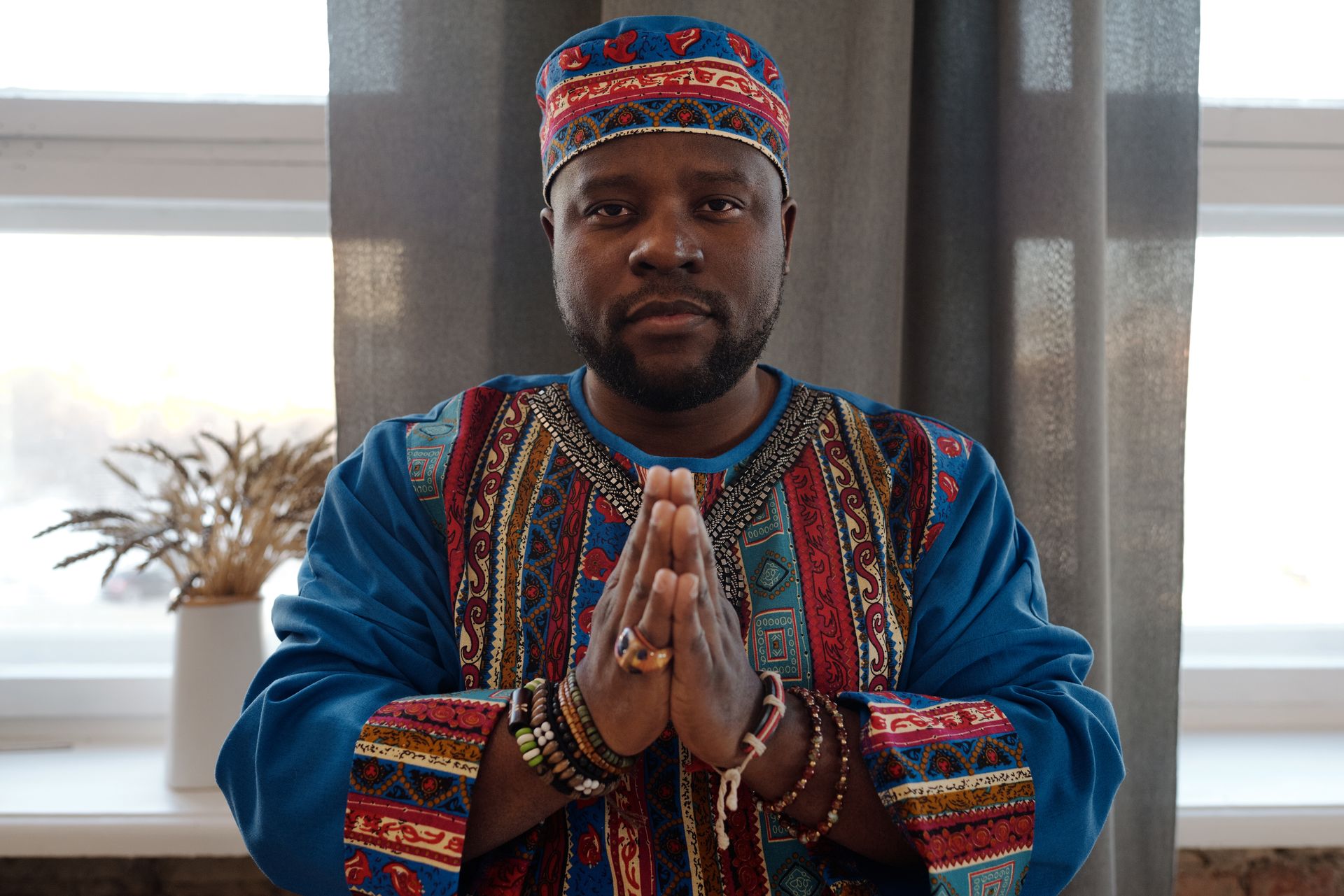A Nigerian man in traditional dress with his hands held together