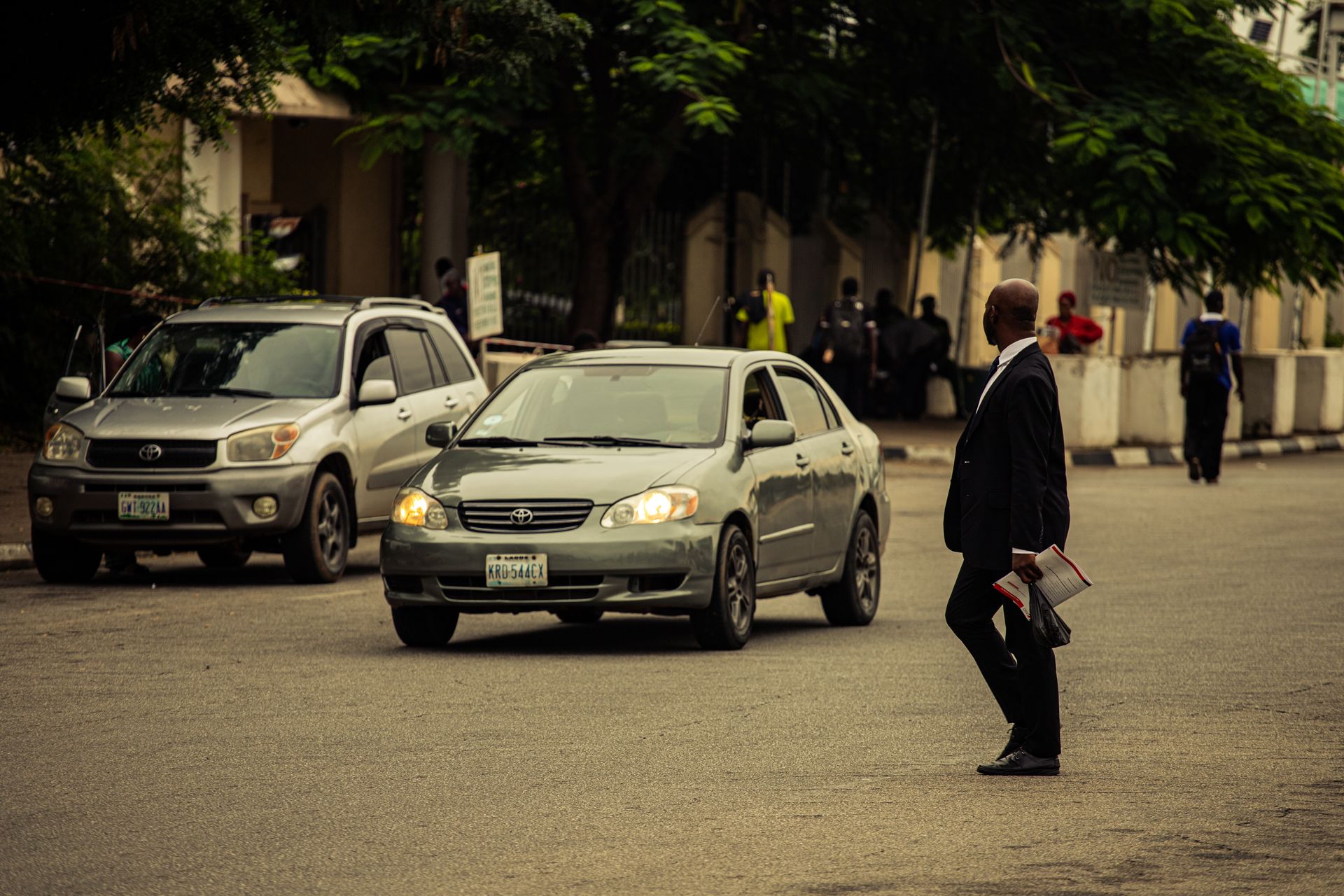 A professional walking past parked cars outside an institutional building in Abuja, Nigeria