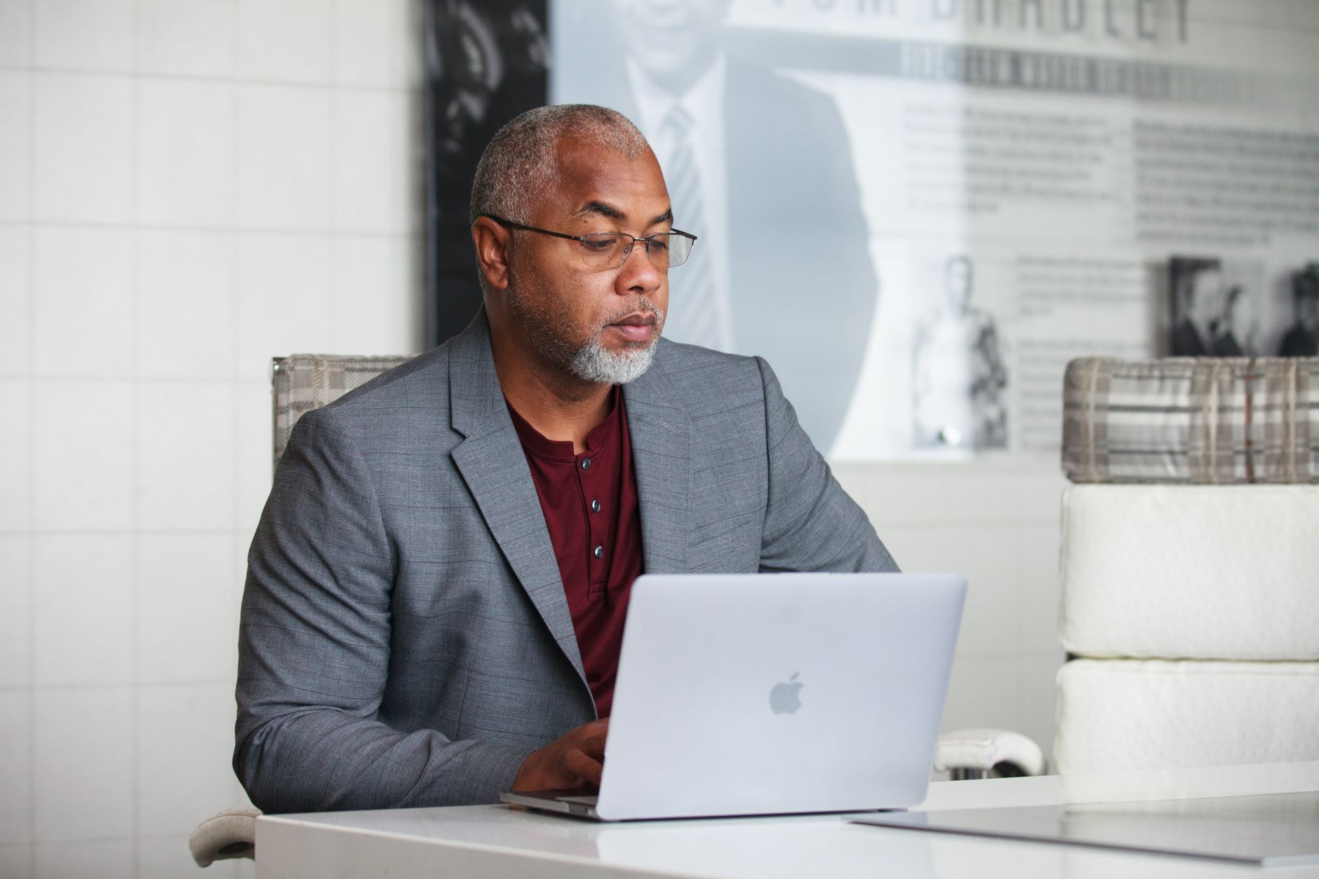 A senior Black executive in a grey blazer presenting from his laptop