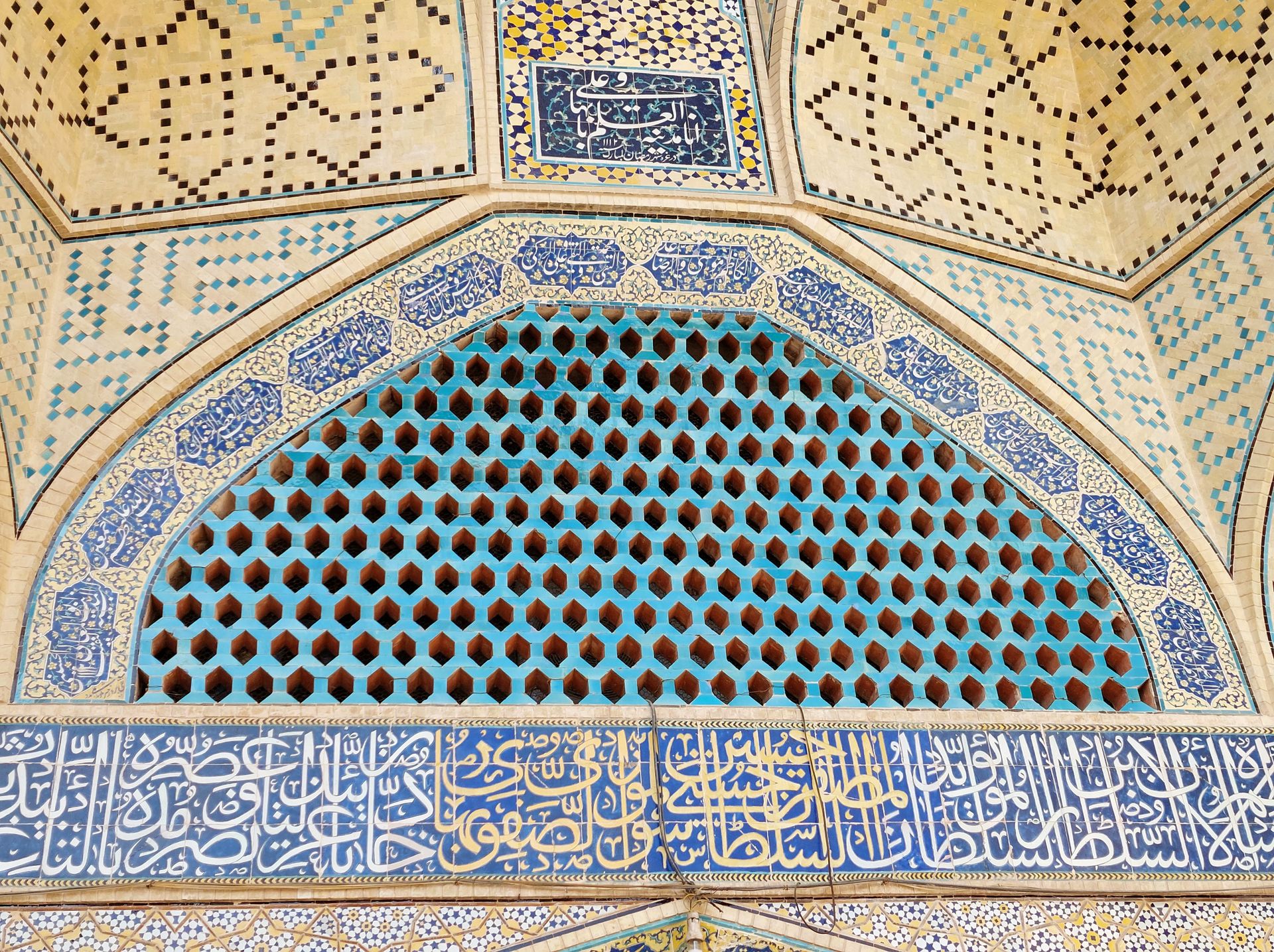 An ornate Islamic tile mosaic featuring Arabic calligraphy and geometric patterns