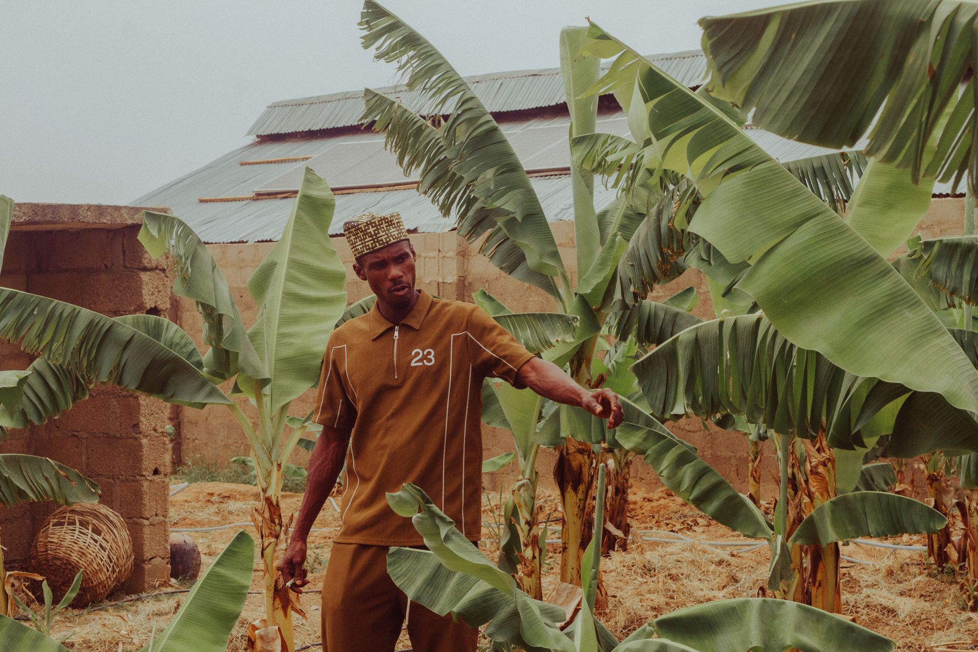A Nigerian man in traditional clothing standing in a plantain farm in Zaria City