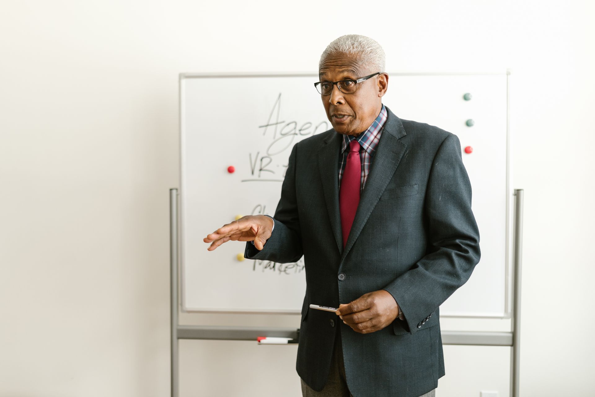 A senior Black executive leading a training session at a whiteboard