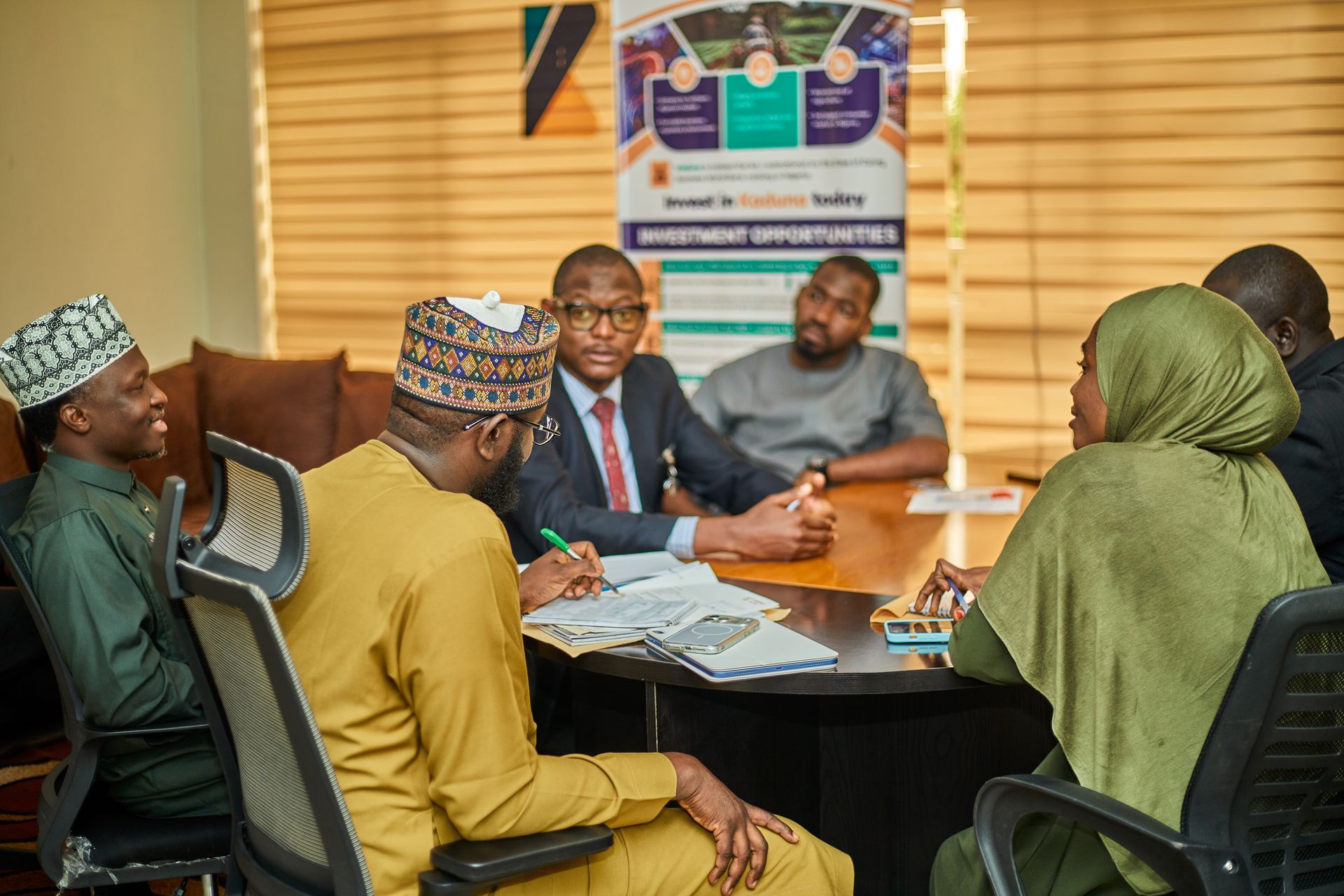 Nigerian financial professionals in traditional dress meeting around a boardroom table in Kaduna